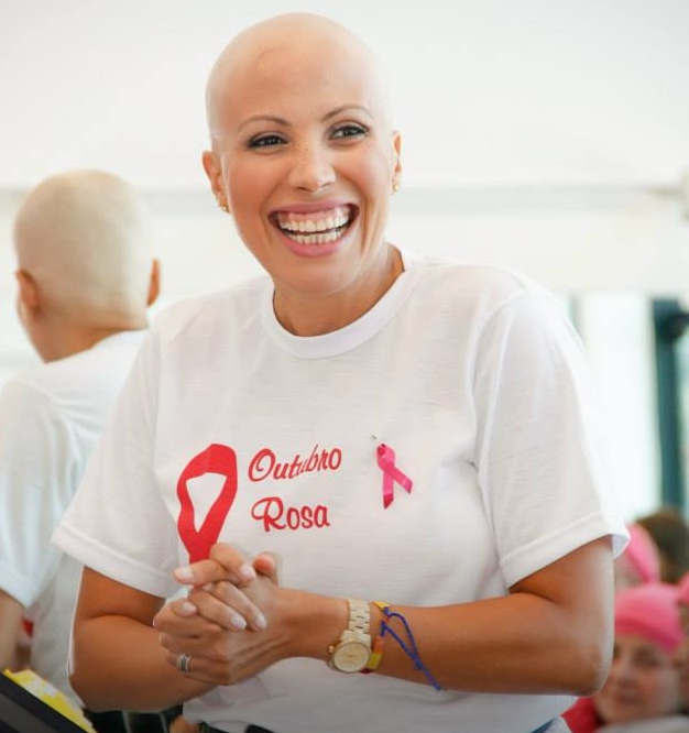 Patrícia durante o tratamento, sorrindo com camiseta Outubro Rosa